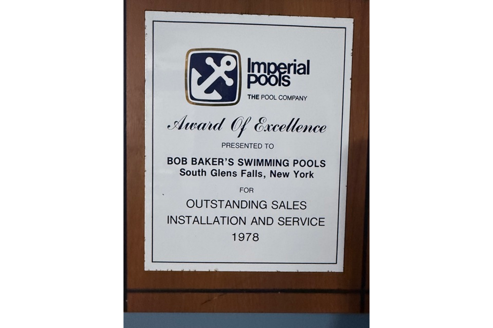 Wooden plaque with the words "Imperial Pools Award of Excellence" written on it